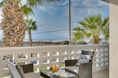 a balcony with a table and chairs and palm trees at Elisabeth Salt Lake views 200m from Makenzy beach in Larnaka