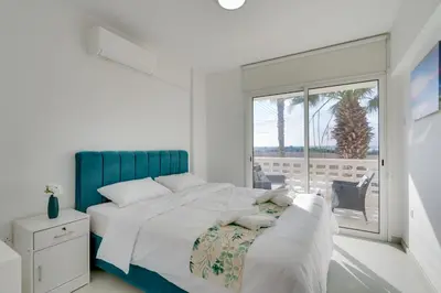 a white bedroom with a large bed and a window at Elisabeth Salt Lake views 200m from Makenzy beach in Larnaka