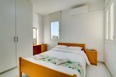 a white bedroom with two beds and two windows at Elisabeth Salt Lake views 200m from Makenzy beach in Larnaka