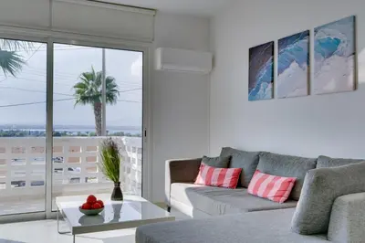 a living room with a couch and a palm tree at Elisabeth Salt Lake views 200m from Makenzy beach in Larnaka