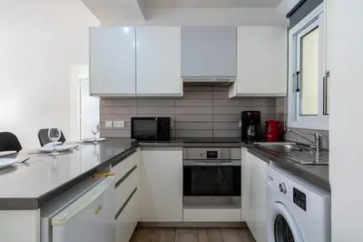 a kitchen with white cabinets and a dishwasher at Levante - 2-BR Apt & Terrace in Larnaca in Larnaka