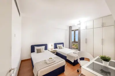 a bedroom with two beds and a table and a desk at Mackenzie Beachfront Suite in Larnaka