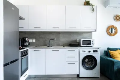 a kitchen with white cabinets and a washing machine at Azoria - Stylish 1-BR Apartment & Balcony in Kiti in Kiti