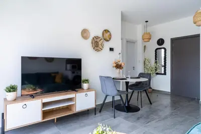 a living room with a tv and a table with chairs at Azoria - Stylish 1-BR Apartment & Balcony in Kiti in Kiti