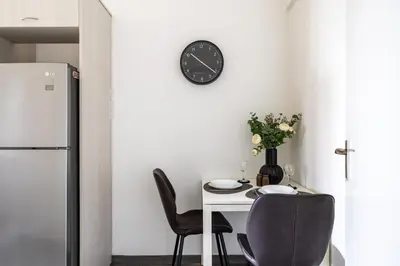 a dining room with a table and a clock on the wall at Bastia - Skyline 1-BR Apt & Balcony in Nicosia in Nicosia