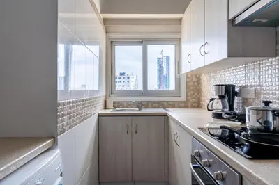 a kitchen with white cabinets and a sink and a window at Bastia - Skyline 1-BR Apt & Balcony in Nicosia in Nicosia