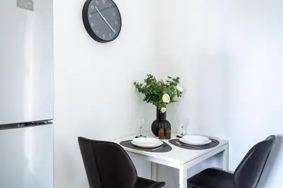 a dining room table with chairs and a clock on the wall at Bastia - Skyline 1-BR Apt & Balcony in Nicosia in Nicosia
