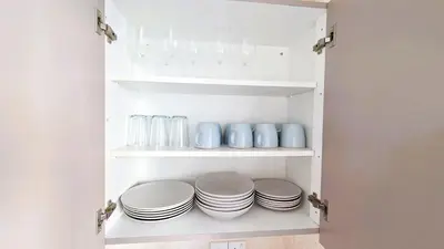 a white cabinet with plates and glasses on it at 2BR Apartment with Pool & Free Wi-Fi in Larnaka