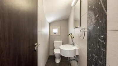 a bathroom with a white toilet and a sink at EcoHarmony Villa in Paralimni