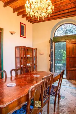 a dining room with a wooden table and a chandelier at The Historical Cypriot House, Beautifully Renovated Traditional Stone House in Ayios Ioannis