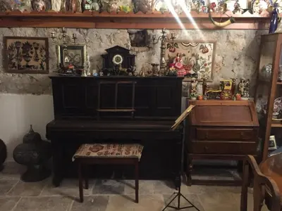 a room with a piano and a bench and a table at Historic 600 years old beautifully renovated Olive Mill House in Meniko