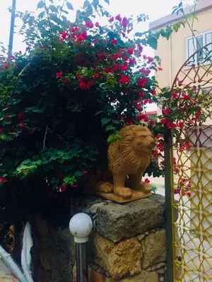 a statue of a lion sitting on a rock with flowers at Historic 600 years old beautifully renovated Olive Mill House in Meniko