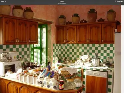 a kitchen with wooden cabinets and a counter top with dishes at Historic 600 years old beautifully renovated Olive Mill House in Meniko