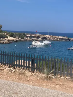 a fence with boats in a body of water at A Home at Coralli - Protaras Beach Apartment, 30 m from beach in Protaras