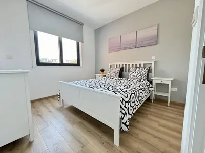 a white bedroom with a bed and two windows at Bright & cozy apartment in Livadia in Livadhia