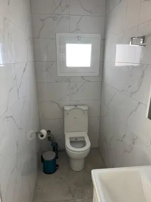 a white bathroom with a toilet and a window at Veray Homes Villa in Ayios Dhometios