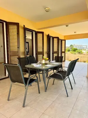 a dining table and chairs on a patio at Aurora Gardens Villa Spacious 3 Bedroom in Protaras in Paralimni