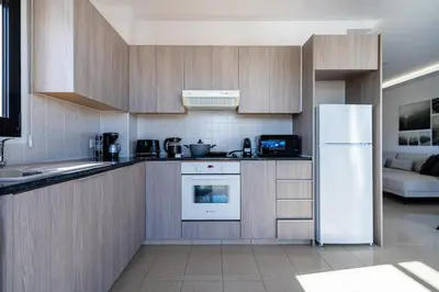 a kitchen with wooden cabinets and a white refrigerator at Averna - Breezy 2-BR Apt & Balcony in Larnaca in Larnaka