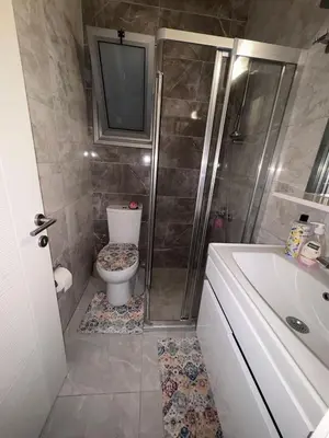 a bathroom with a shower and a toilet and a television at Lapta Purple 2 bedroom in Peristerona