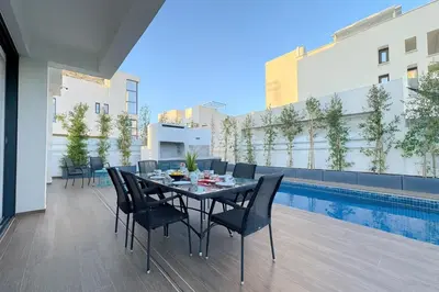 a dining area with a table and chairs and a pool at Sunrise Pearl - 2 min walk to Sirena Bay in Paralimni