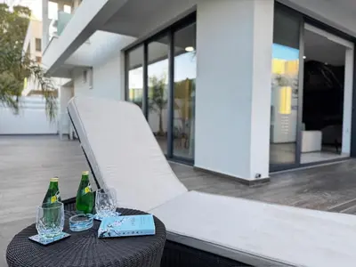 a table with two bottles and glasses on a patio at Sunrise Pearl - 2 min walk to Sirena Bay in Paralimni
