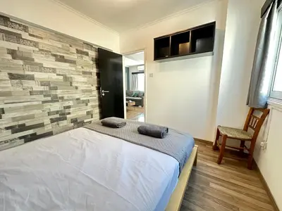 a bedroom with a bed and a brick wall at Serenity Home - Holiday Apt Larnaca in Larnaka