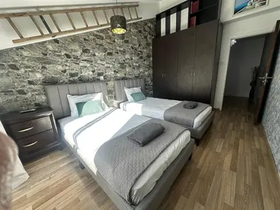 a bedroom with two beds and a stone wall at Serenity Home - Holiday Apt Larnaca in Larnaka