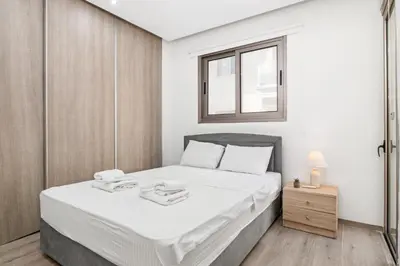 a bedroom with a bed with white sheets and a window at Downtown 2 Bedroom City Flat in Larnaka