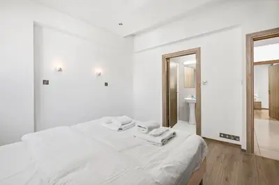 a white bedroom with a bed with towels on it at Downtown 2 Bedroom City Flat in Larnaka
