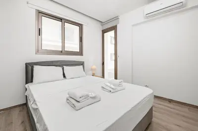 a white bedroom with a bed with towels on it at Downtown 2 Bedroom City Flat in Larnaka