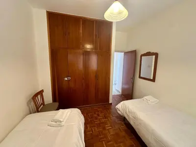 a room with two beds and a wooden cabinet at 2 bedroom flat by the sea in Larnaka