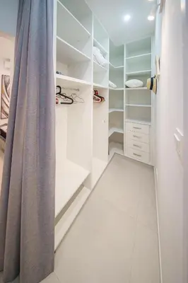 a walk in closet with white shelves and a curtain at Villa Oro Hills w private hot tub jacuzzi in Voroklini