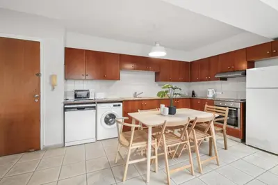 a kitchen with wooden cabinets and a table and chairs at Downtown Stadium 3 Bedroom Apartment in Larnaka