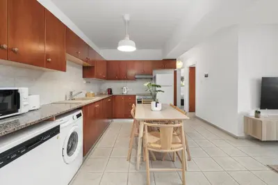 a kitchen with wooden cabinets and a table with a plant on it at Downtown Stadium 3 Bedroom Apartment in Larnaka