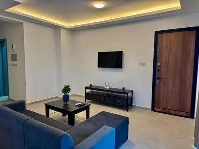 a living room with a couch and a tv and a table at Soğular Apartments 1 in Aglantzia