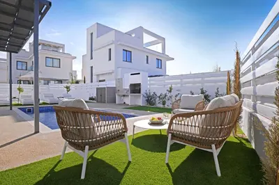 a patio with two chairs and a table in front of a building at Villa Elizabeth - Pernera Resort Center in Paralimni