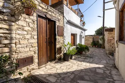 a stone house with a wooden door on a street at Villa Monti Cozy Yard & BBQ Perfect for Families & Friends in Kato Lefkara
