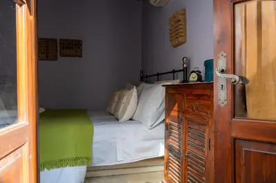 a bedroom with a bed with white sheets and a wooden door at Villa Monti Cozy Yard & BBQ Perfect for Families & Friends in Kato Lefkara