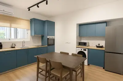 a kitchen with blue cabinets and a table and chairs at Cozy Boho 2-BR Retreat in Central Nicosia in Nicosia