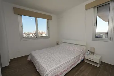 a white bedroom with a bed and two windows at Larnaca Salt Lake Gem, Airy 2 BDRM Apartment in Larnaka