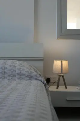 a bed with a lamp on a table with a window at Larnaca Salt Lake Gem, Airy 2 BDRM Apartment in Larnaka