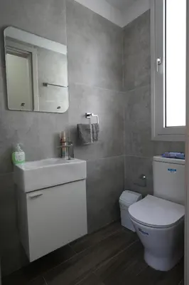 a bathroom with a toilet and a sink and a mirror at Larnaca Salt Lake Gem, Airy 2 BDRM Apartment in Larnaka