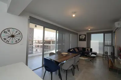 a dining room and living room with a clock on the wall at Larnaca Salt Lake Gem, Airy 2 BDRM Apartment in Larnaka