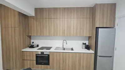 a kitchen with wooden cabinets and a sink and a refrigerator at STAY Engomi Gem 2 in Engomi