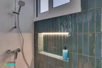 a bathroom with a shower with a blue tiled wall at Lordos Deluxe 2bd Duplex with pool and Seaview in Larnaka