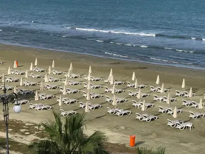 a beach with white umbrellas and the ocean at Panoramic Sea View Apartments in Larnaka