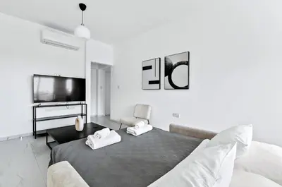 a white bedroom with a bed and a tv at STYLE Limassol by Ezoria Villas in Limassol
