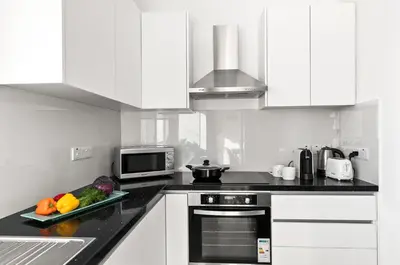 a kitchen with white cabinets and a plate of vegetables at STYLE Limassol by Ezoria Villas in Limassol