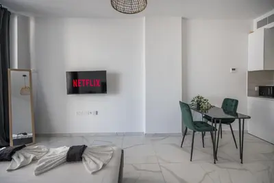 a living room with a table and green chairs at Mackenzie Signature Studio Suite in Larnaca in Larnaka