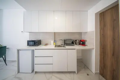 a kitchen with white cabinets and a sink at Mackenzie Signature Studio Suite in Larnaca in Larnaka